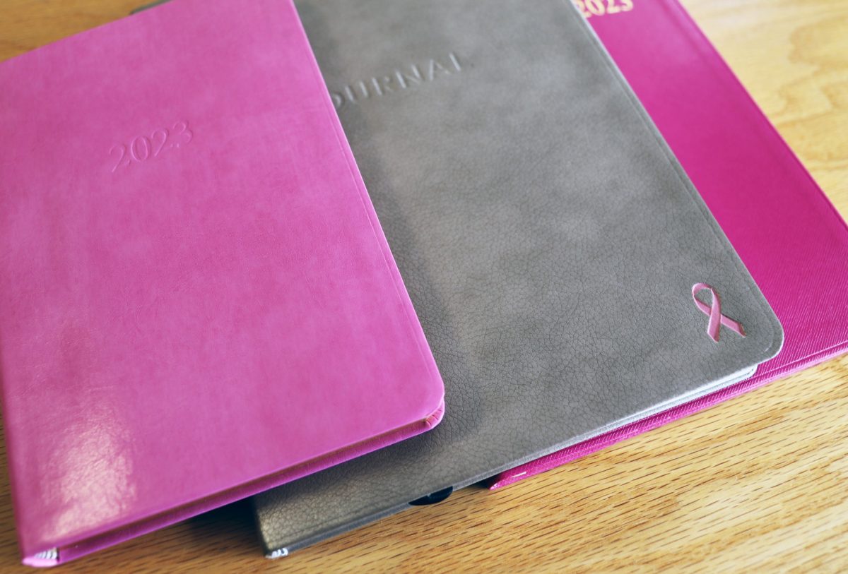 group of planners and journals with a pink breast cancer ribbon personalization