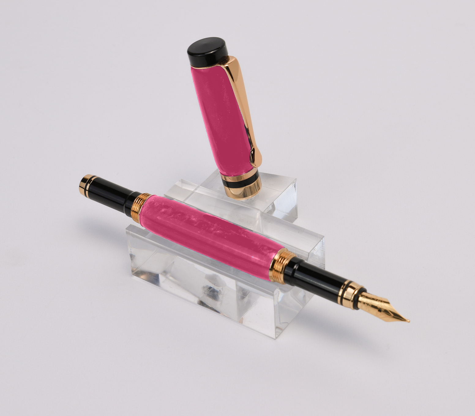 A cotton candy pink fountain pen sitting sideways on a white background with the cap off.